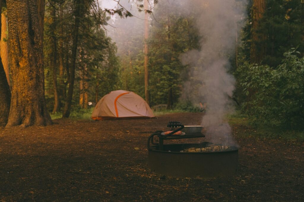 a campfire near a tent in the woods