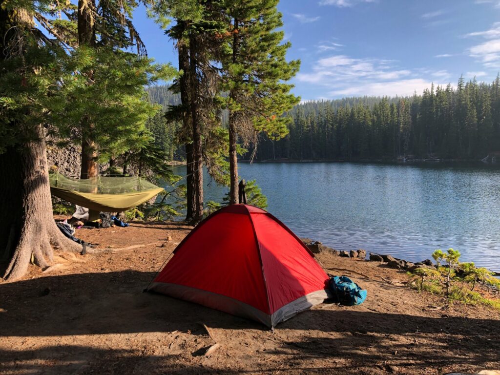 Red and black tent near a lake