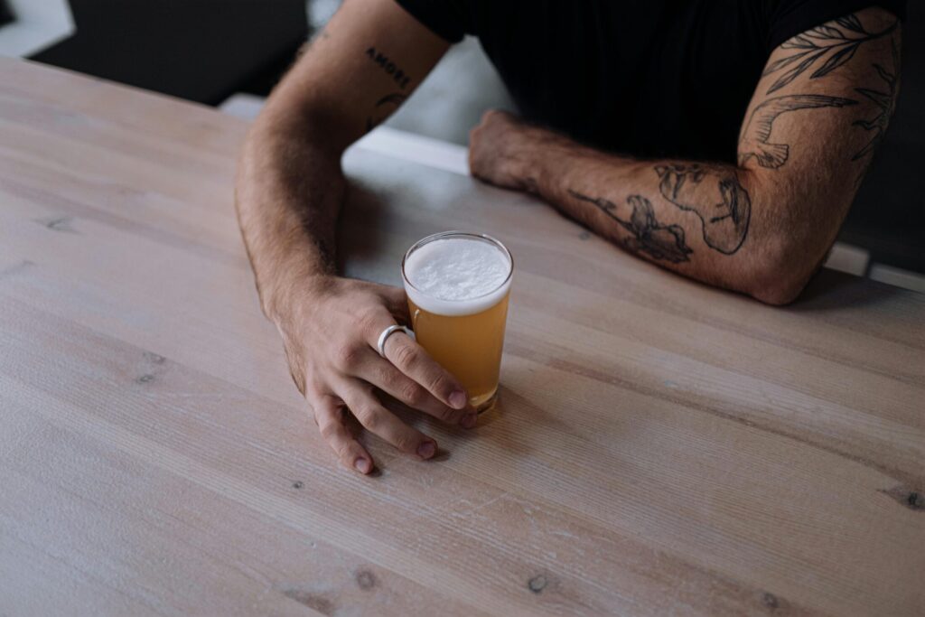 Photo of a Person's Hand Holding a Glass of Beer