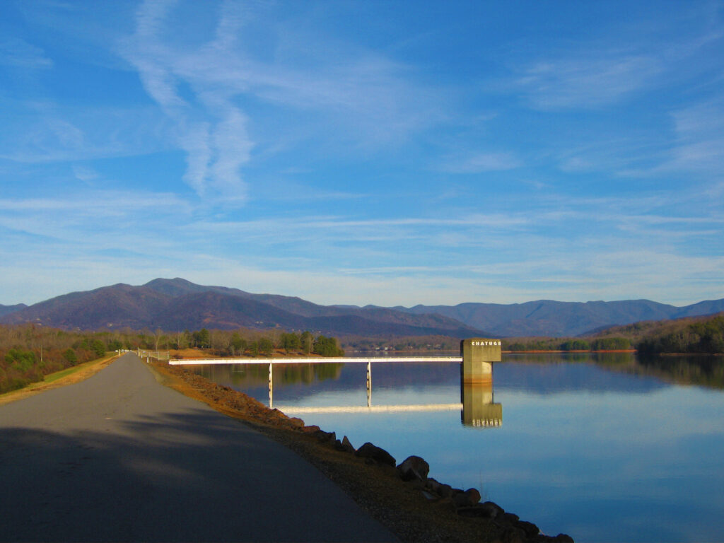 a paved road with the views of Lake Chatuge dam