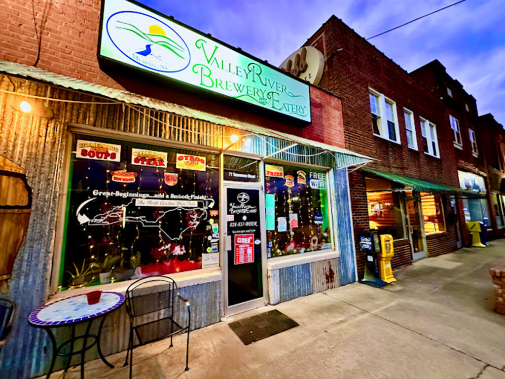 the exterior of the Valley River Brewery & Eatery in Murphy, NC, lit up at dusk.