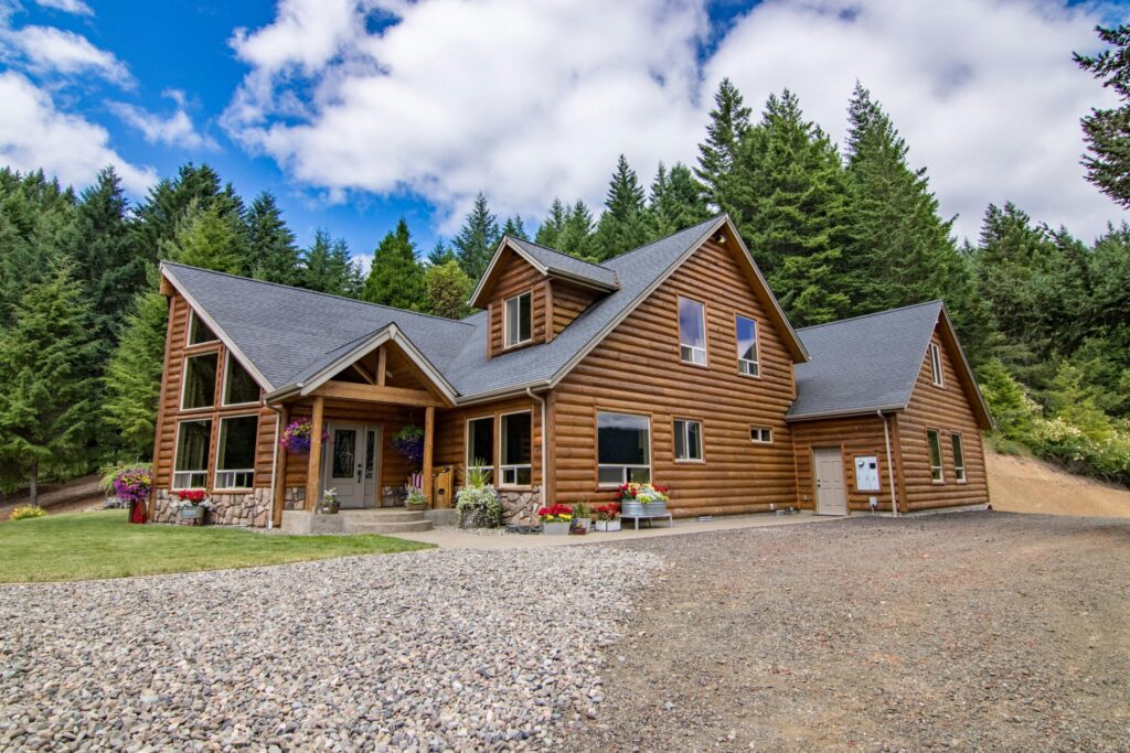 a brown log cabin surrounded by green trees